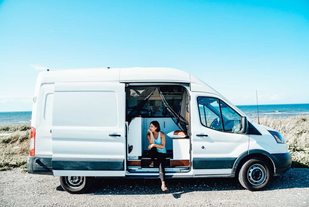 Ford Transit camper van with girl sitting in sliding door