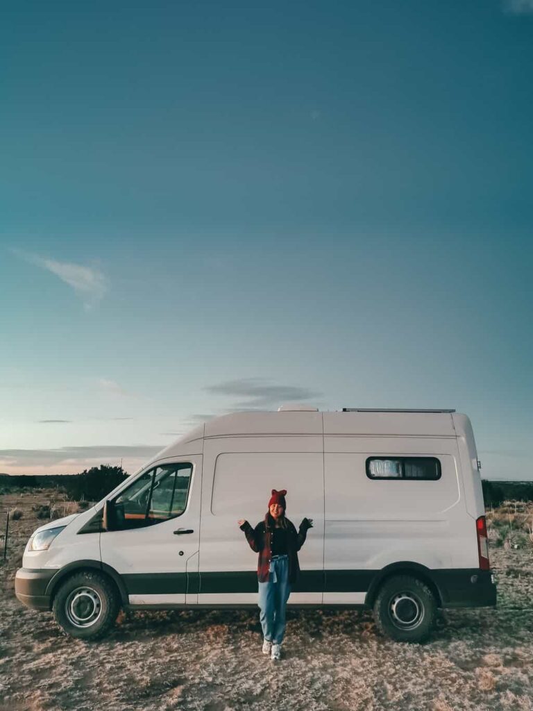 A woman posing outside her camper van