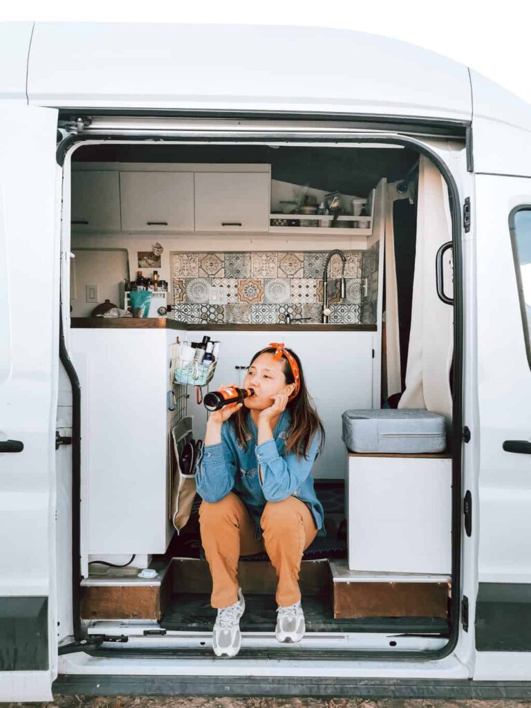 Woman drinking beer and relaxing inside her campervan