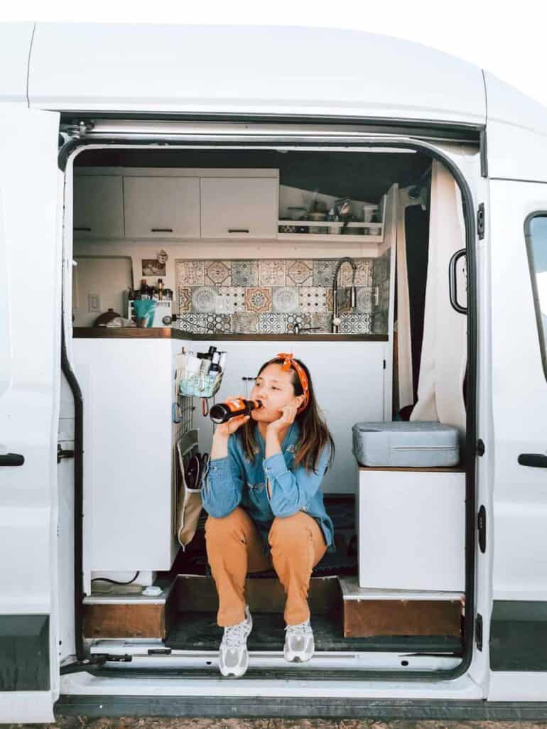 Woman drinking beer and relaxing inside her campervan