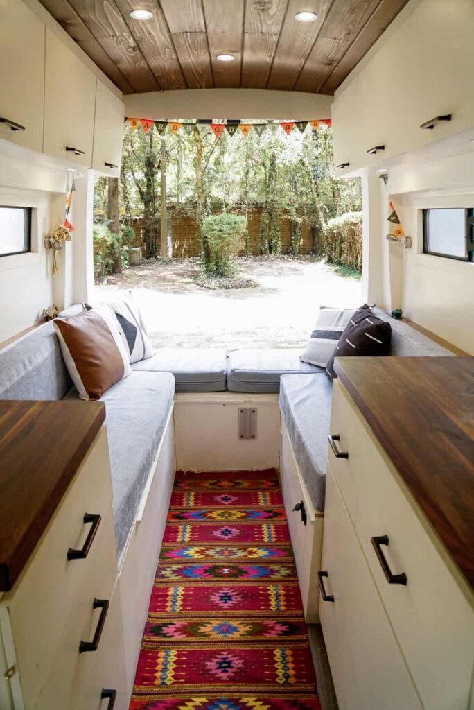 Inside a camper van with cabinets, bed, and rug