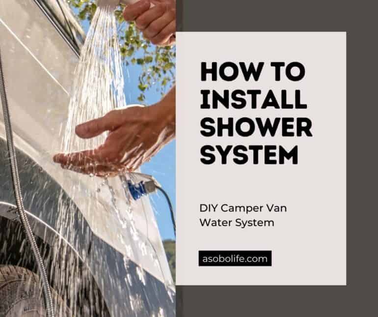 A hand holding a running shower head next to a camper van