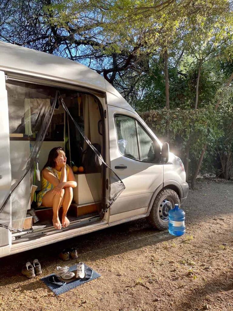 Yuko sitting inside a camper van looking out into a campsite