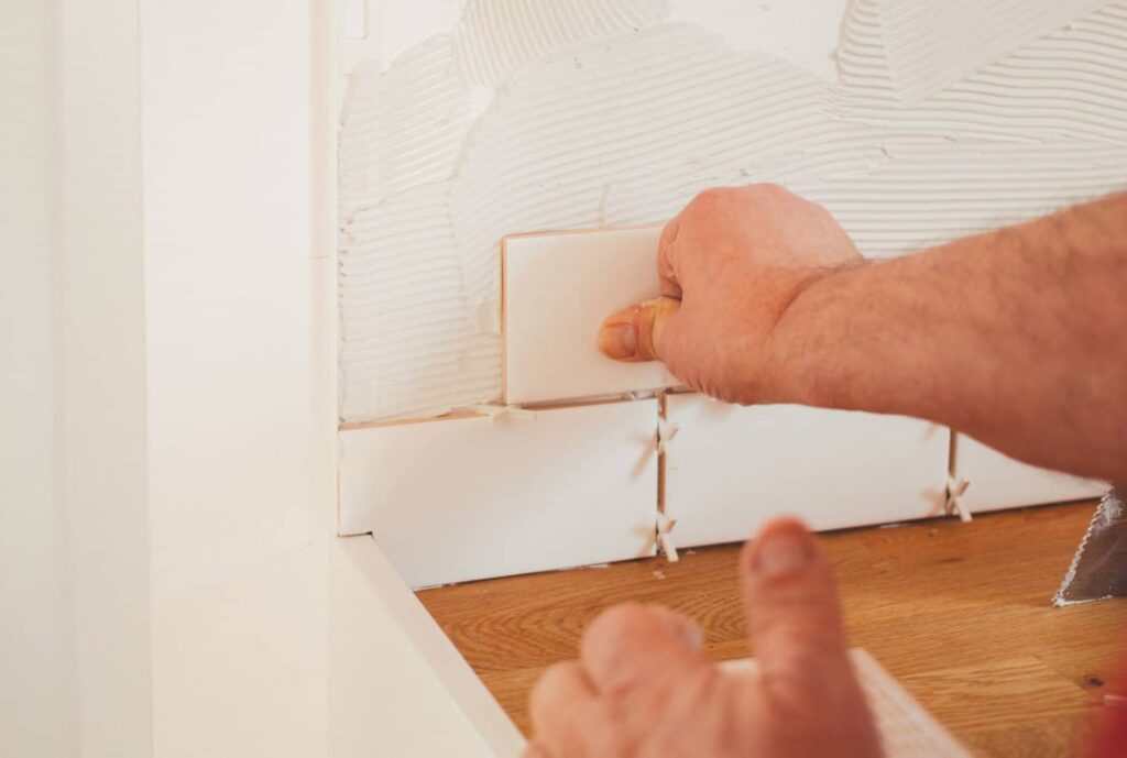 Man installing tiles on a while