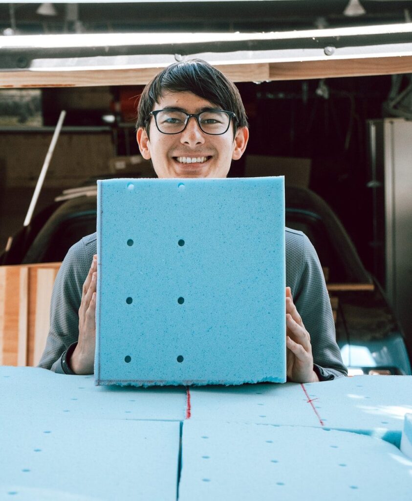 Man displaying a square foam mattress cutout.