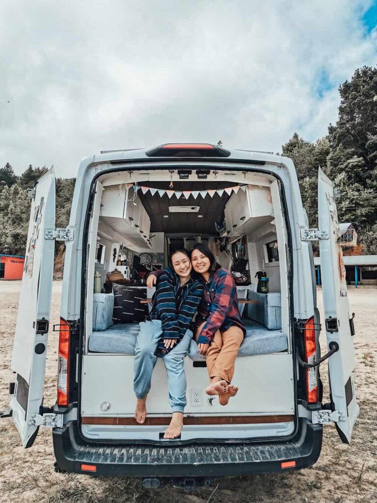 Two women sitting inside a camper van