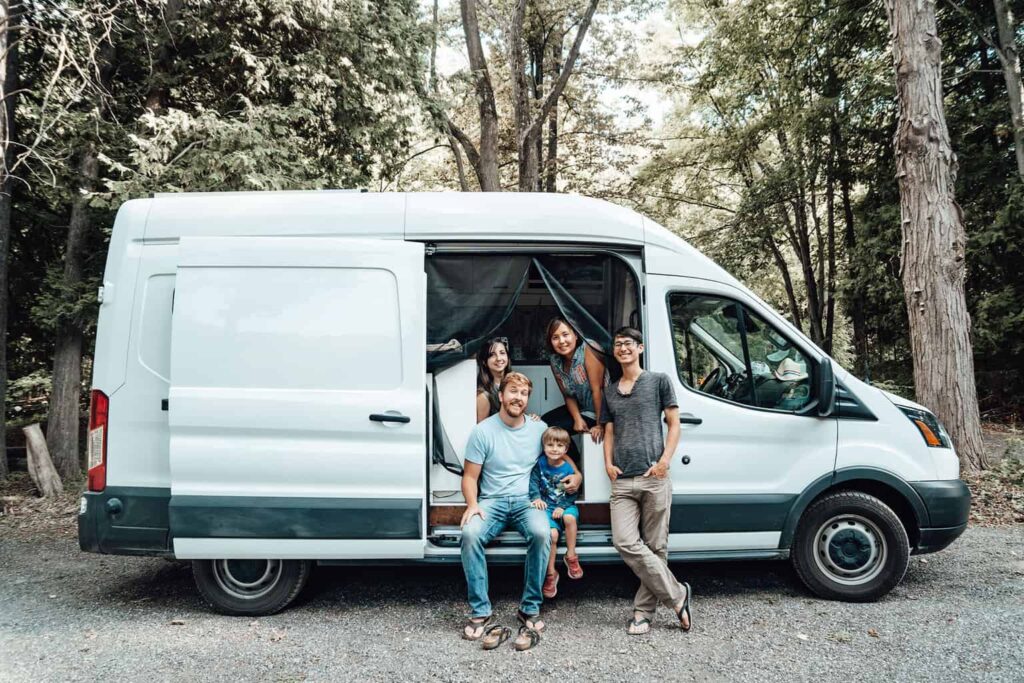 Two couples standing in front of an open camper van