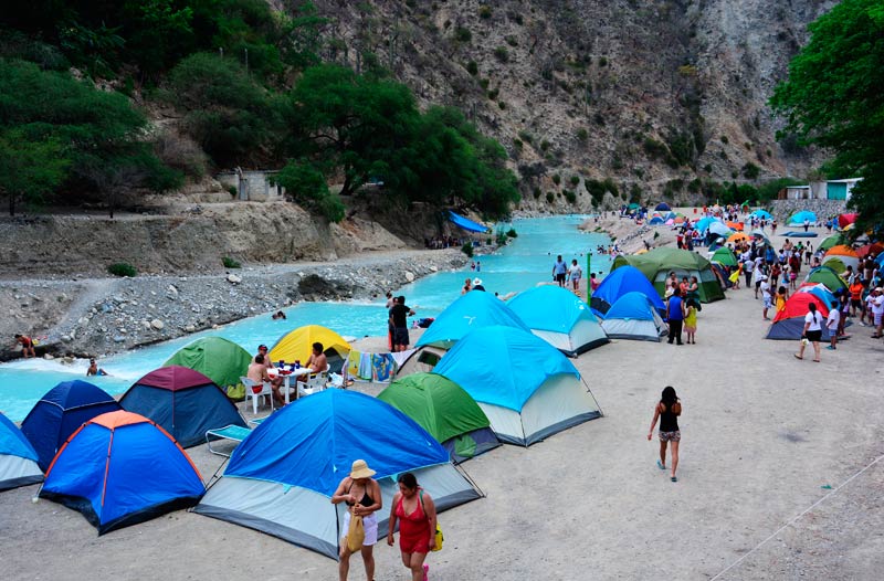 People and tents hanging out by the river at Grutas de Tolantongo