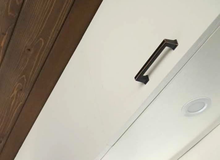 Brushed bronze handle installed on a white overhead cabinet front