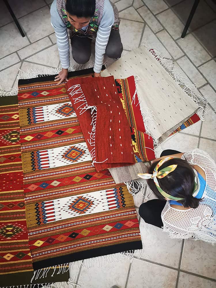 Yuko going through different wool rugs in a store in Oaxaca, Mexico