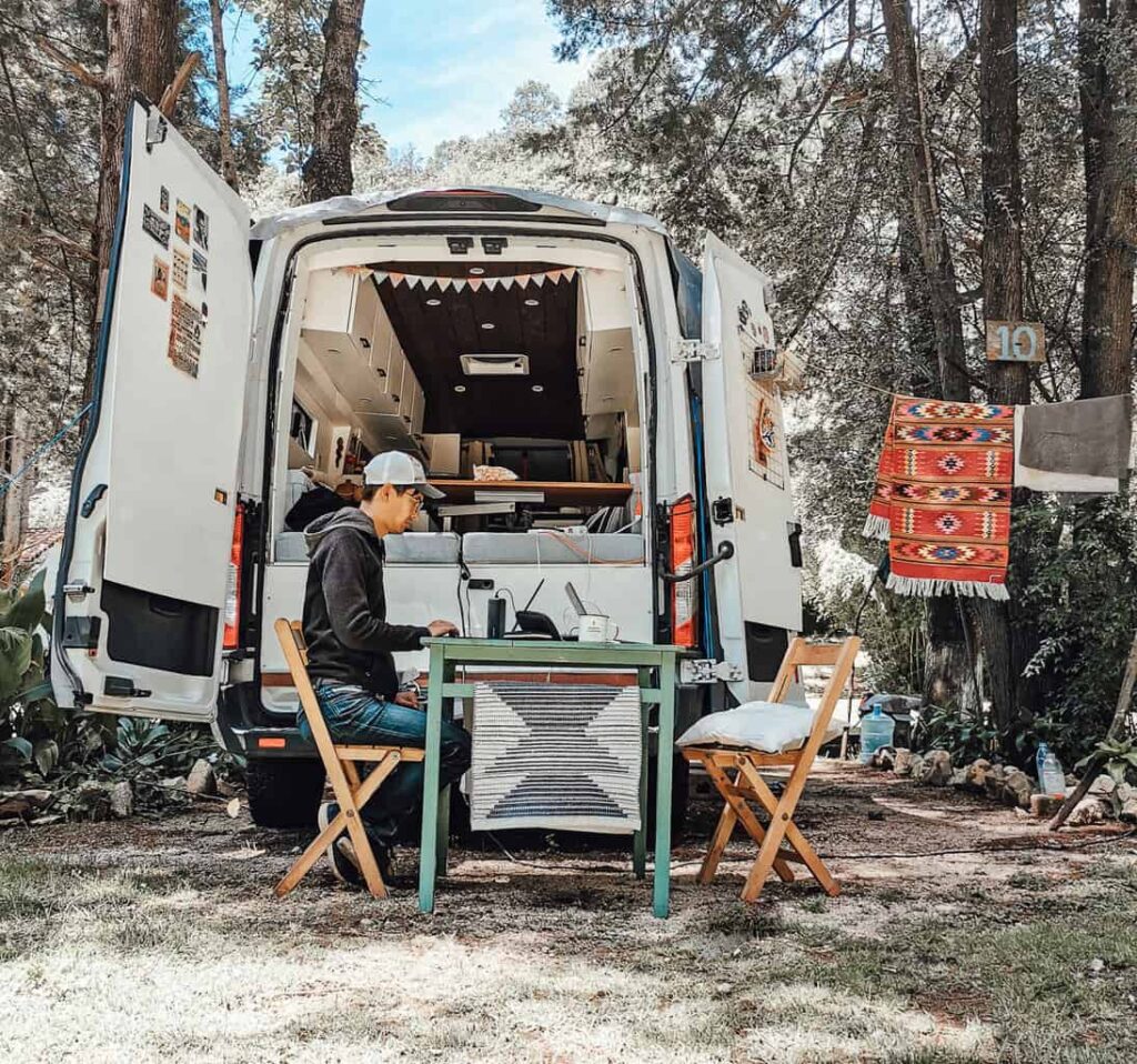 Eric working on his laptop from the back of a camper van