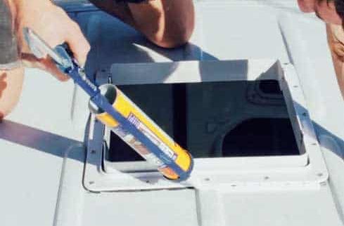 Person applying silicone sealant around the vent fan flange