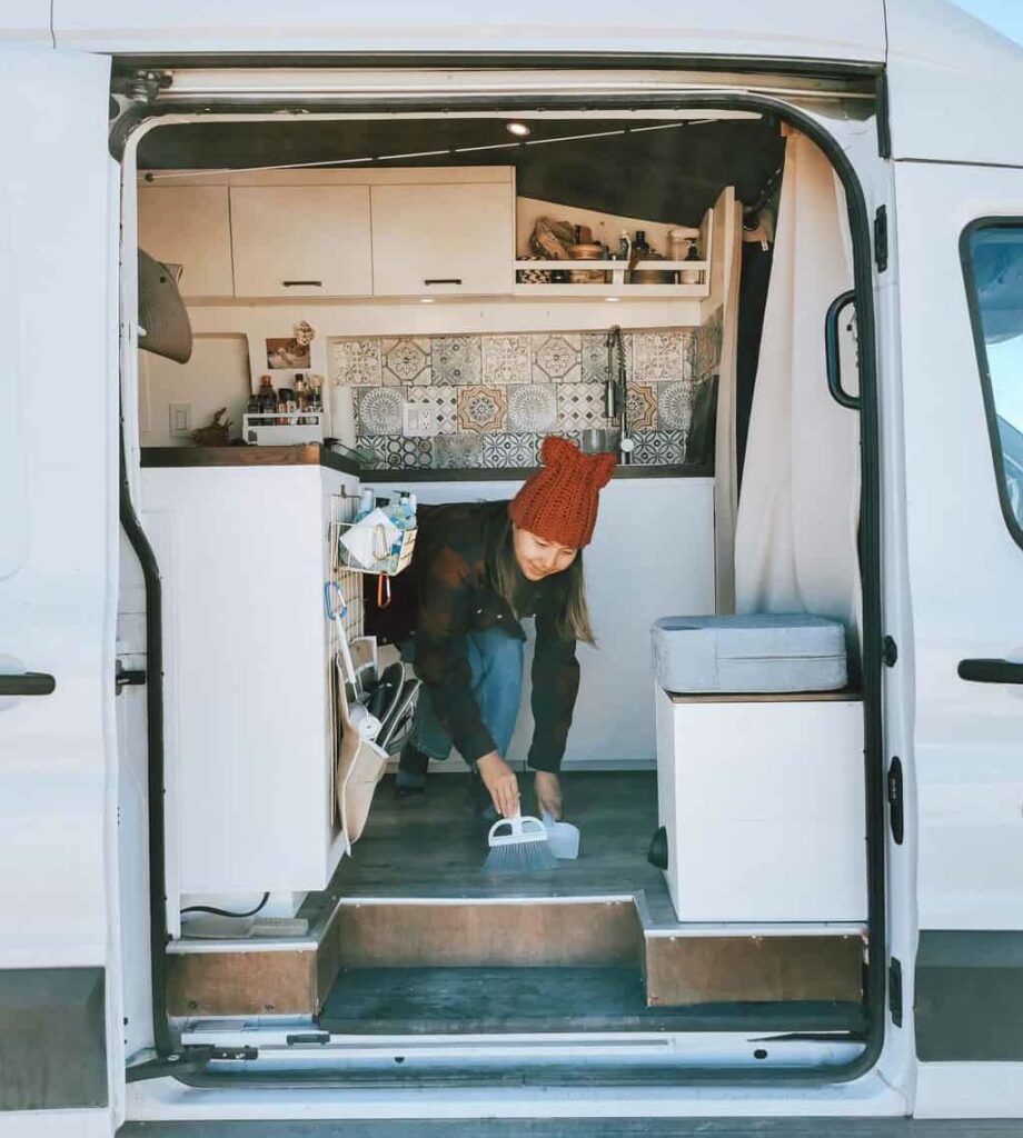 Woman sweeping the floor of her camper van