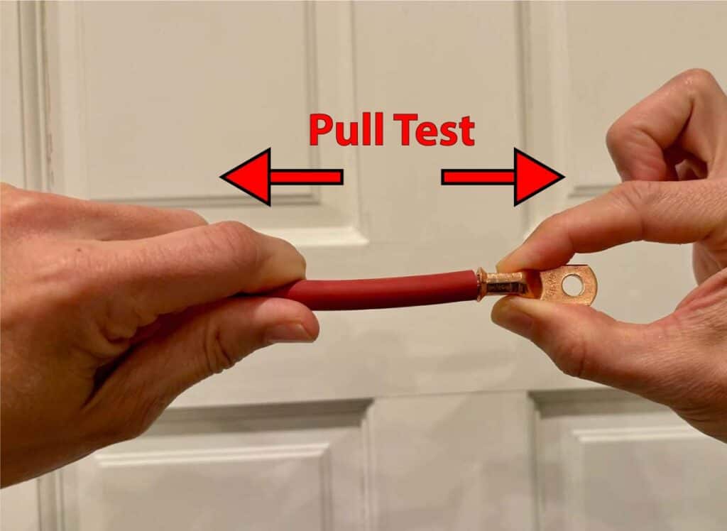 Two hands attempting to pull the wire out from the lug.