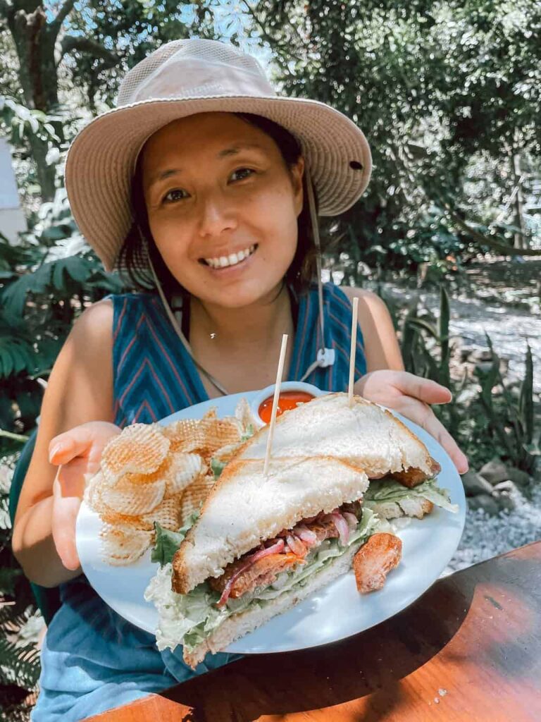 Woman showing off her sandwich lunch at Valhalla Macadamia Nut Farm in Antigua, Guatemala