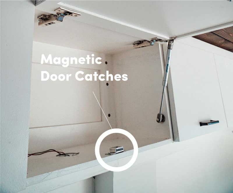 Magnetic door catch installed on white overhead cabinets