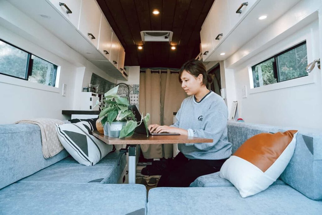 Woman working on a laptop inside a camper van