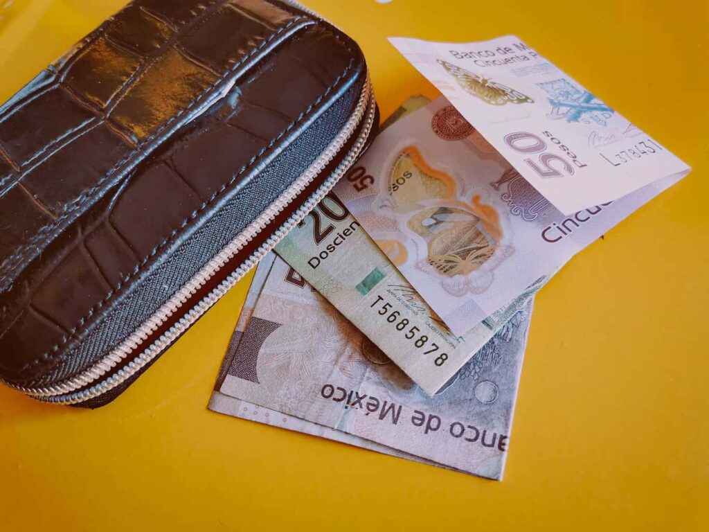 Mexican peso bills and a wallet on a table