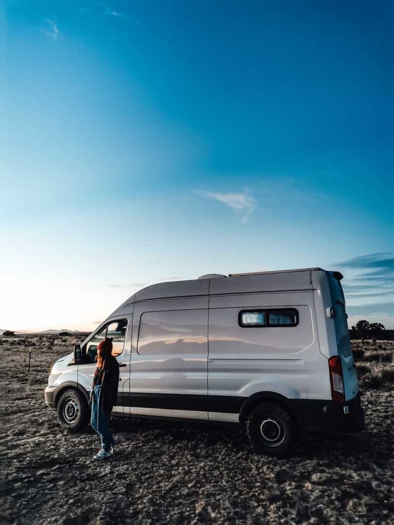 Woman standing outside her camper van that is parked on BLM land