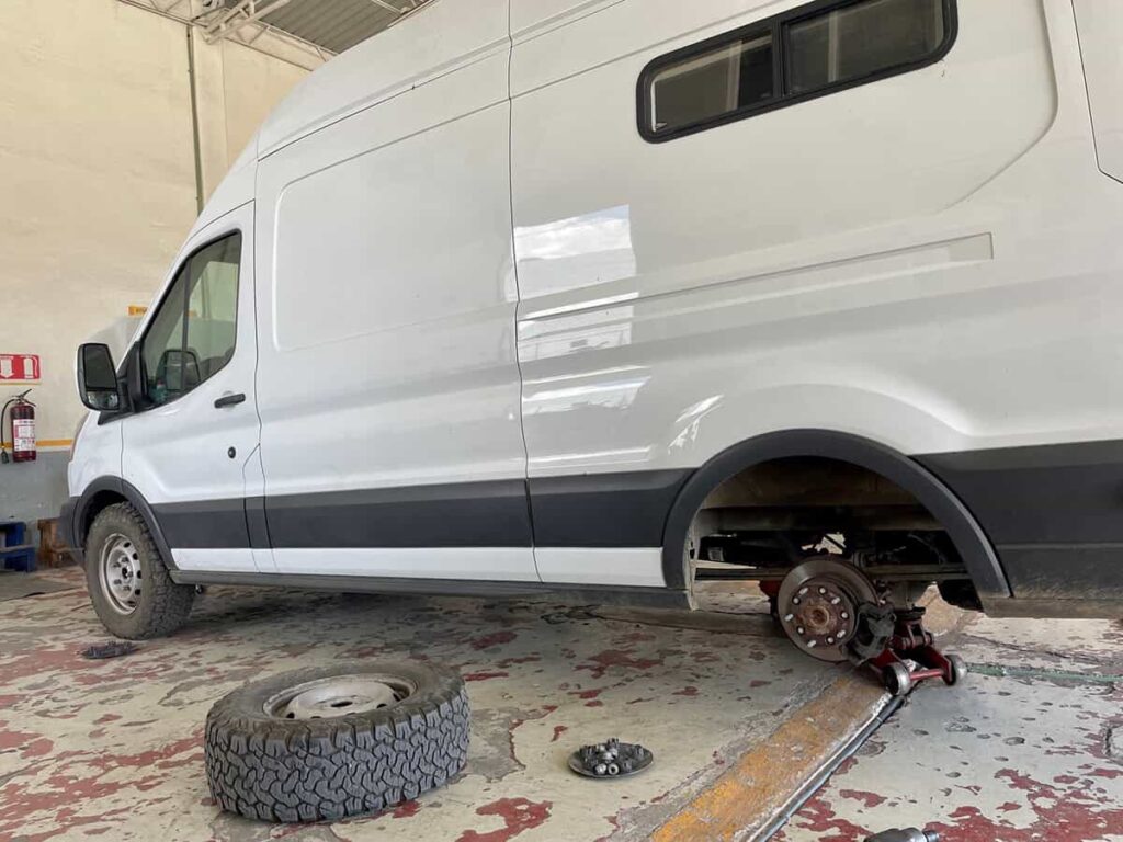 Replacing brake pads on a Ford Transit camper van at an auto shop in Mexico