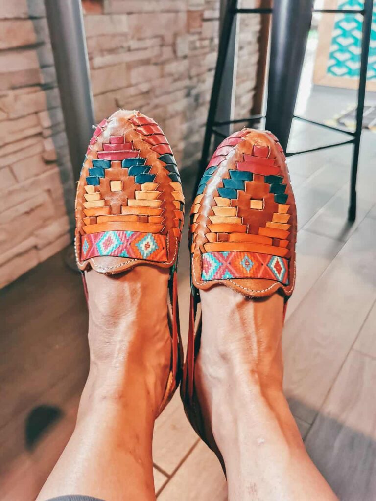 Two feet wearing a pair of Mexican colorful leather shoes