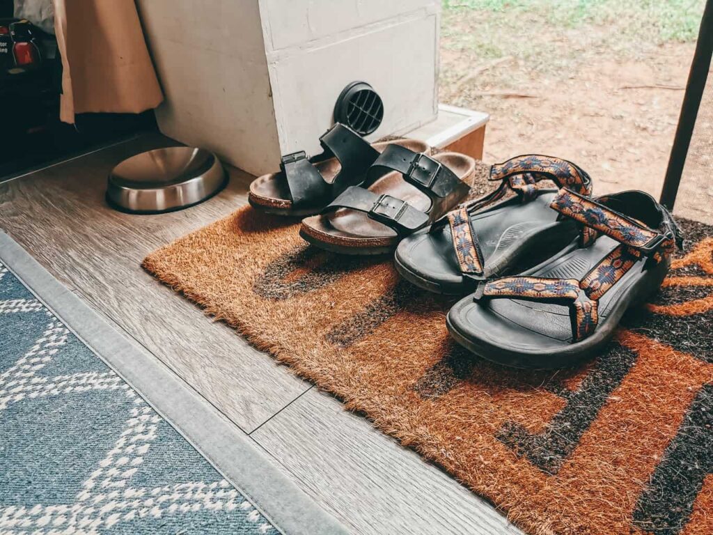 Two pairs of shoes on a welcome mat at the entrance of a camper van