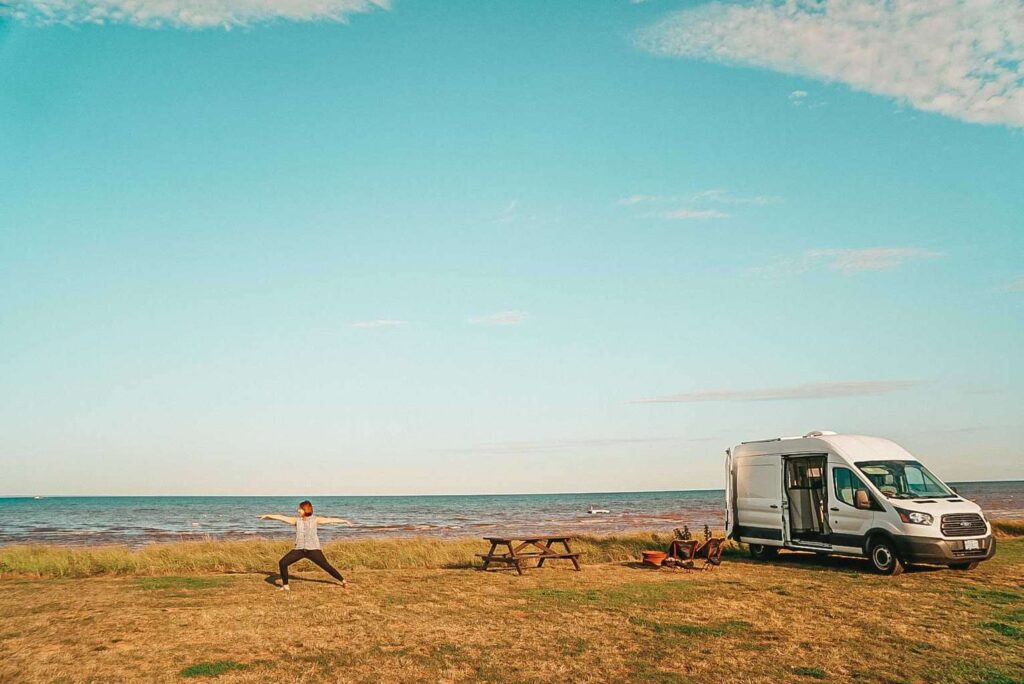 Woman practicing yoga next to a camper van