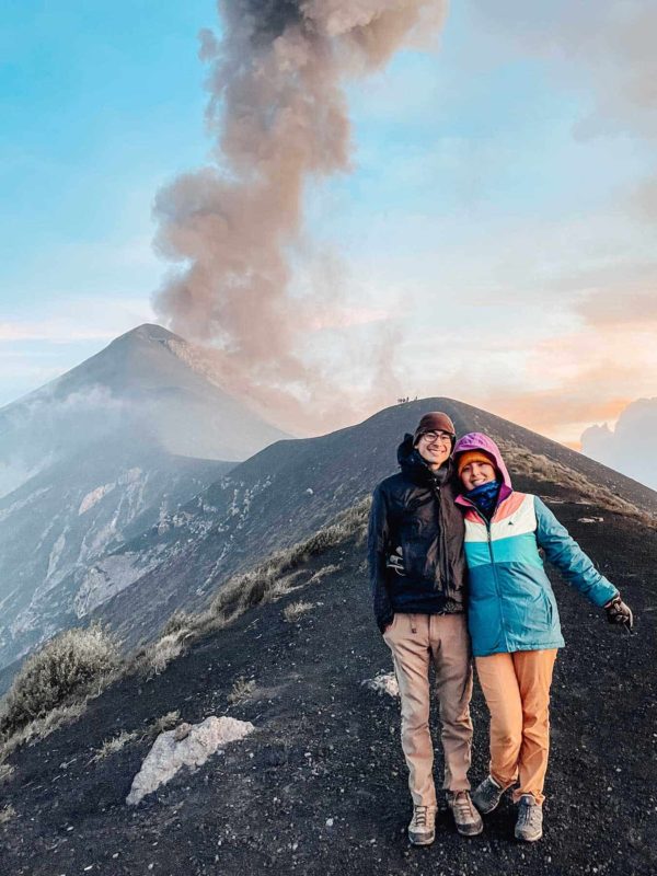 Couple standing in front of Fuego Volcano at sunset