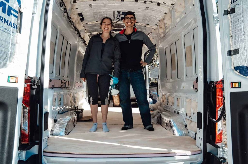 Two people standing inside a DIY camper van