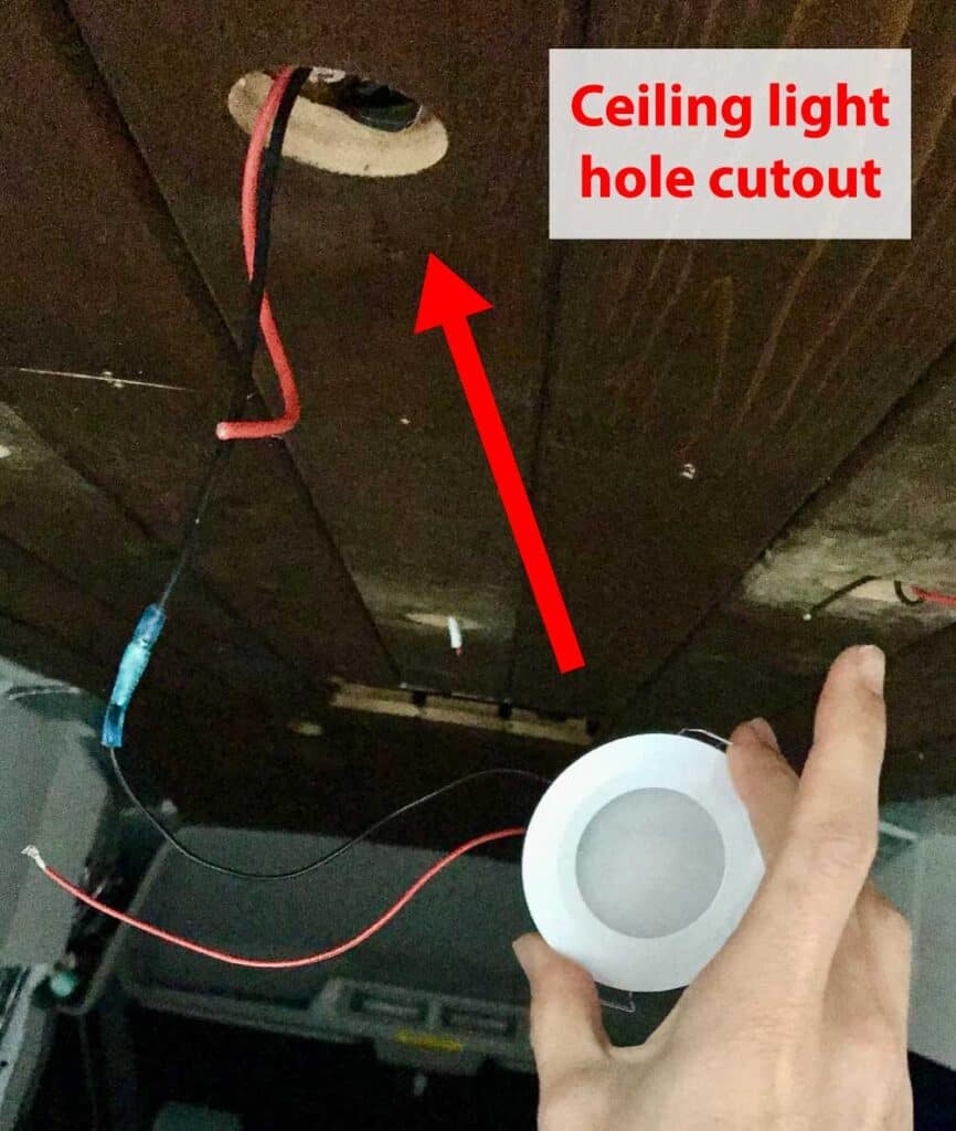 About to insert a 12V puck light into the holes we cut out in the ceiling plank.