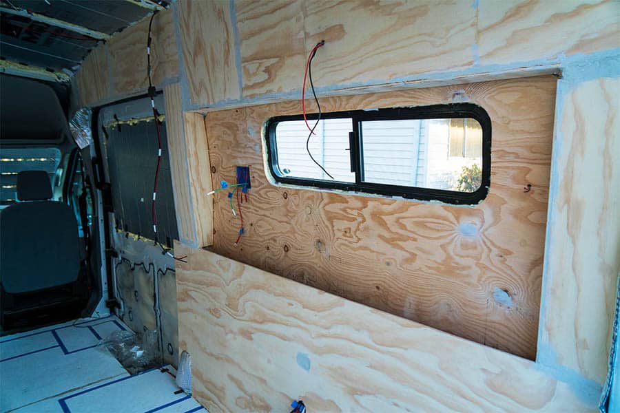 Camper van window surrounded by plywood walls