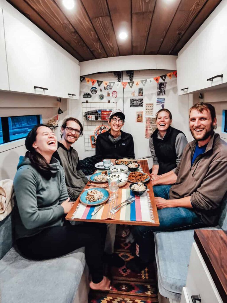 Five adults eating dinner in a camper van