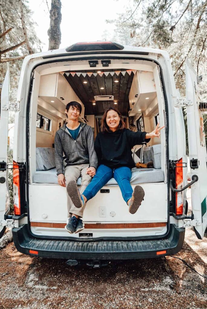 Couple posing for a photo out the back of their camper van