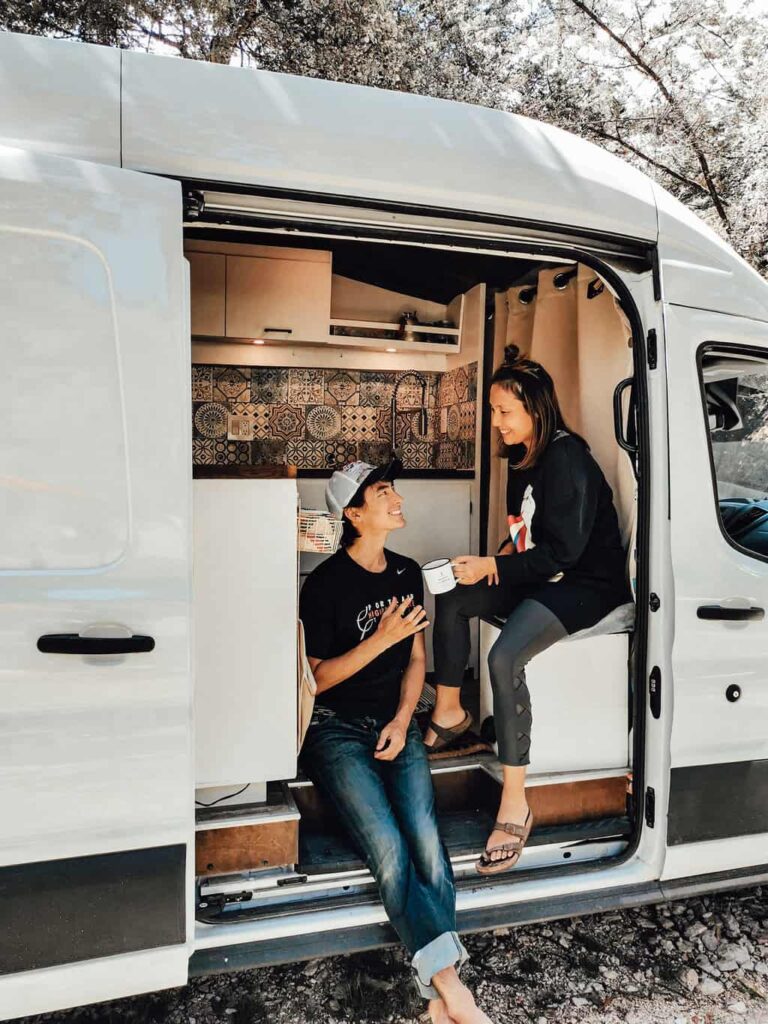 Couple drinking coffee in the morning in their camper van