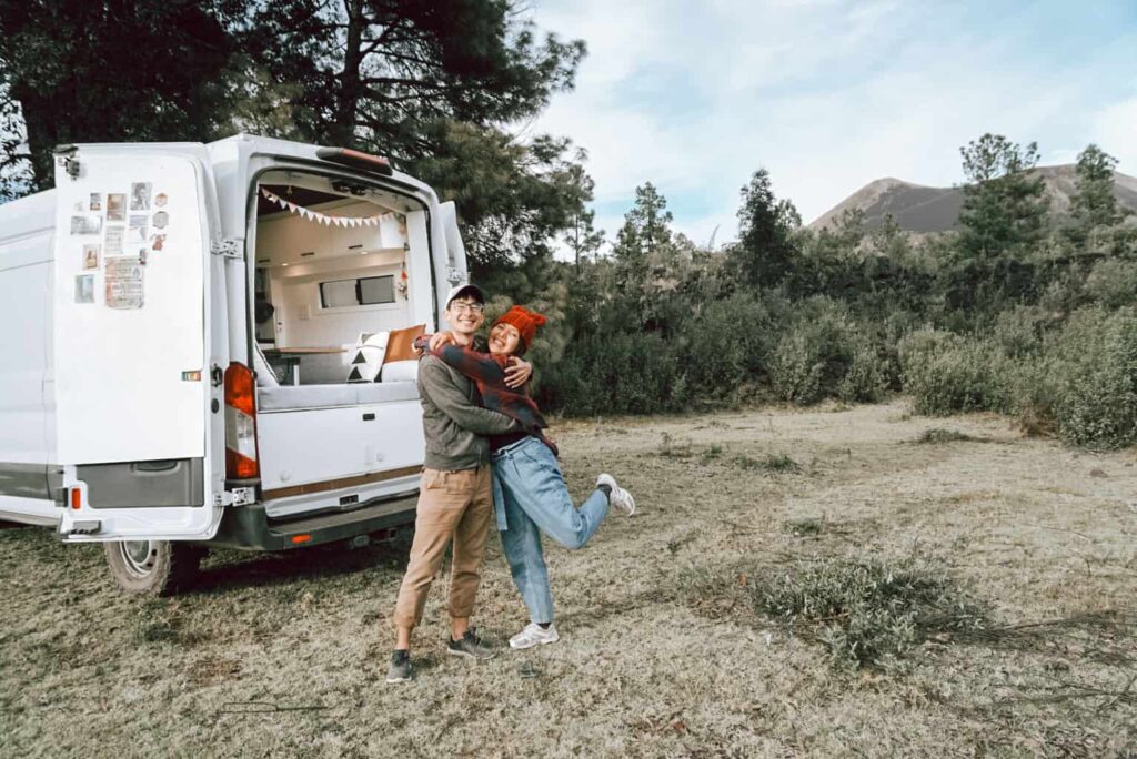 Couple hugging each other in front of their camper van