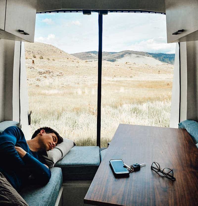 Eric sleeping inside a camper van with the back doors open