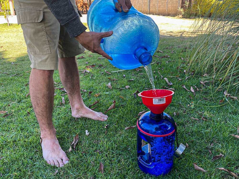 Pouring water from a large 5 gallon tank to a smaller 1 gallon tank