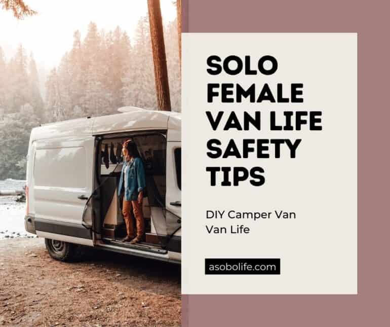 A woman standing inside a camper van by herself and looking out towards a river