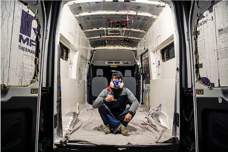 Eric sitting inside a camper van after painting the interior walls