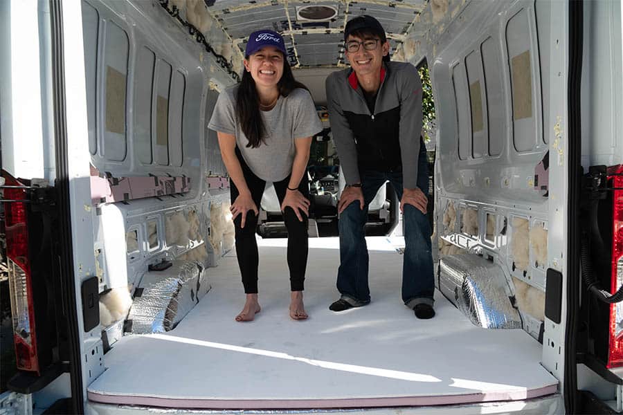 Two people standing on a completed van subfloor