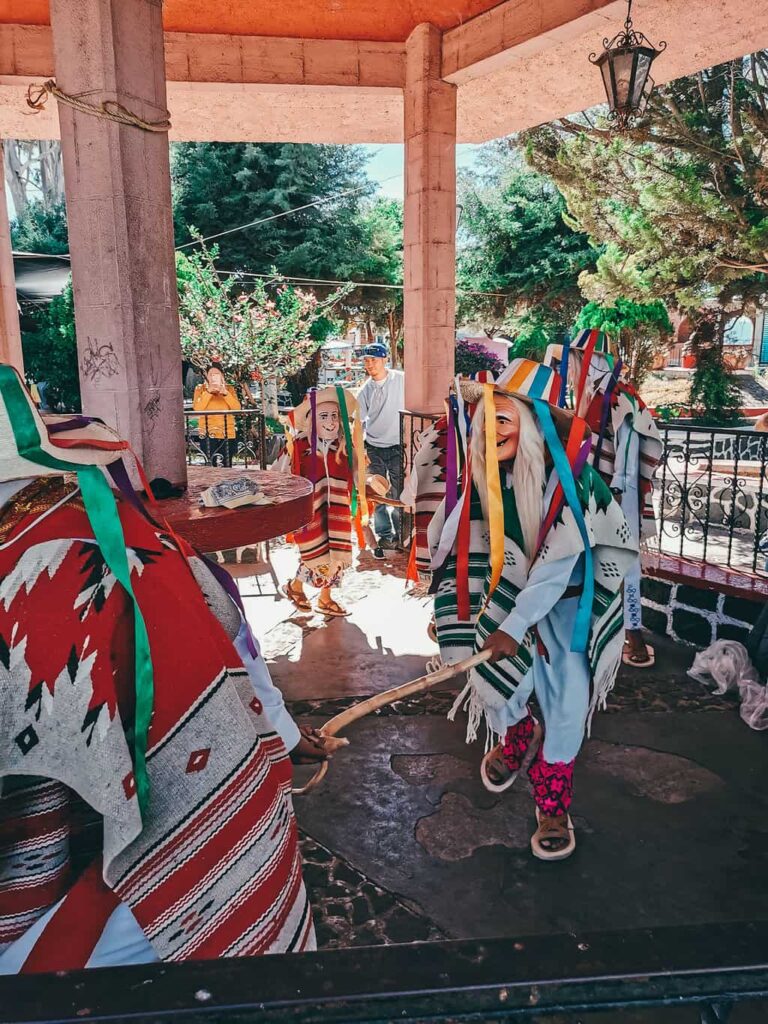 Old men in traditional costume dancing inside a pagoda
