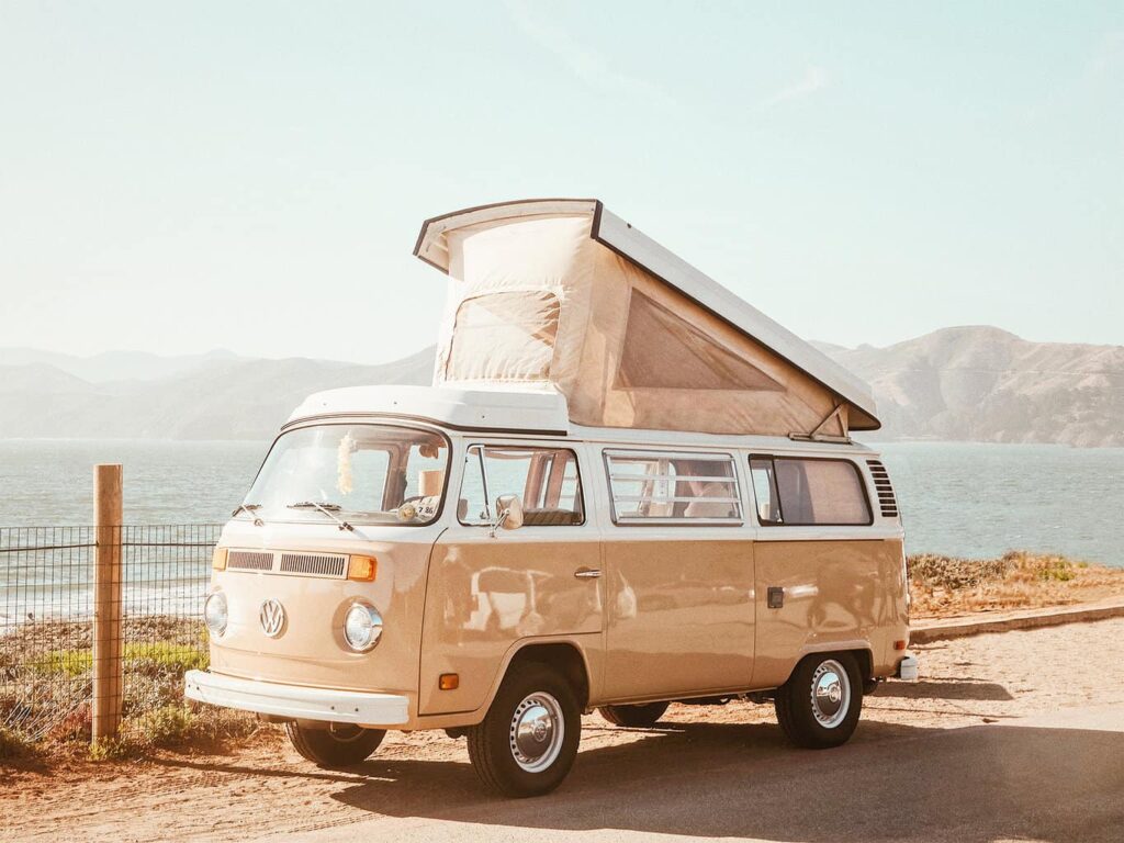 Pink VW combi van parked by the water