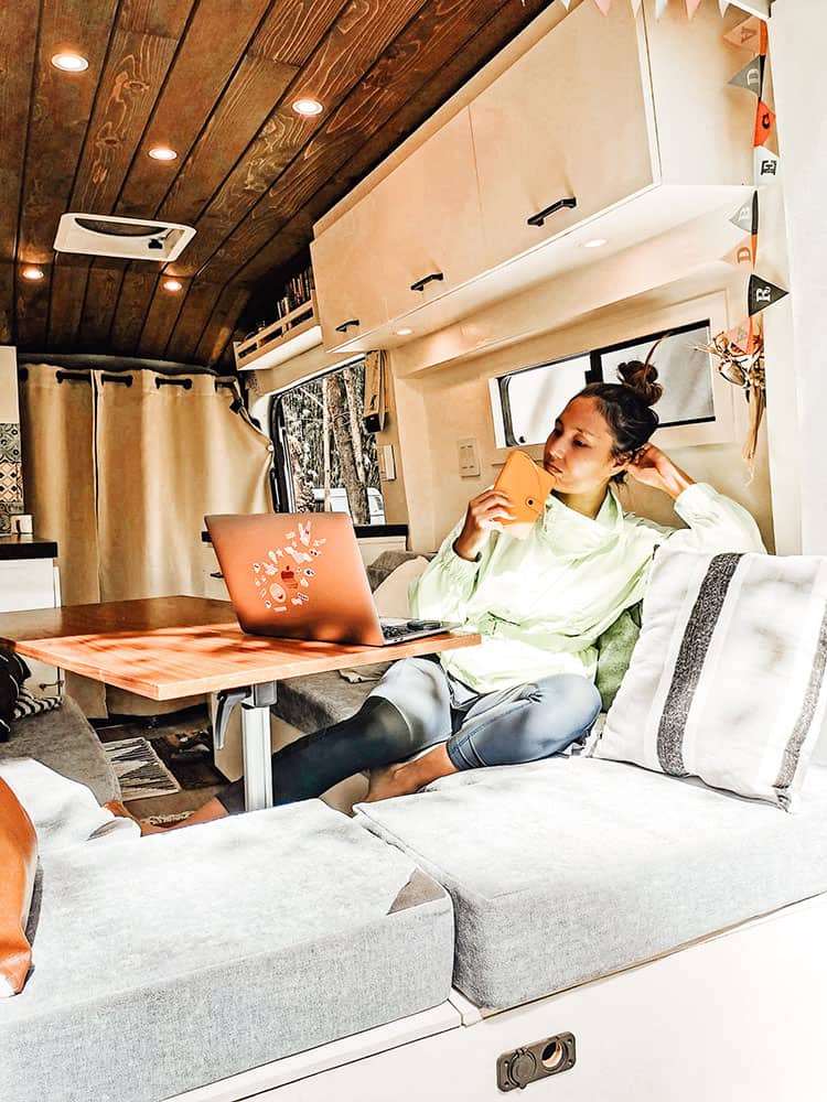 Woman working on a laptop while sitting inside a camper van