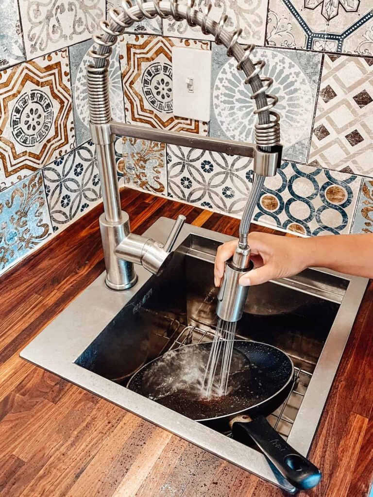 Faucet spraying water in the middle of a sink in a camper van.