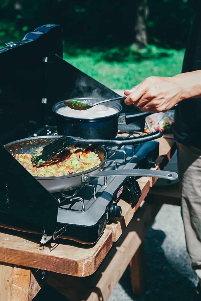 Cooking outside on a picnic bench with a Coleman camping stove