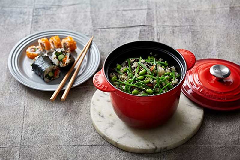 Le Creuset cast iron rice pot with rice inside and side of sushi